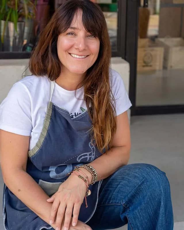 Flor, la dueña de Oui, sentada en la puerta del local con delantal de trabajo